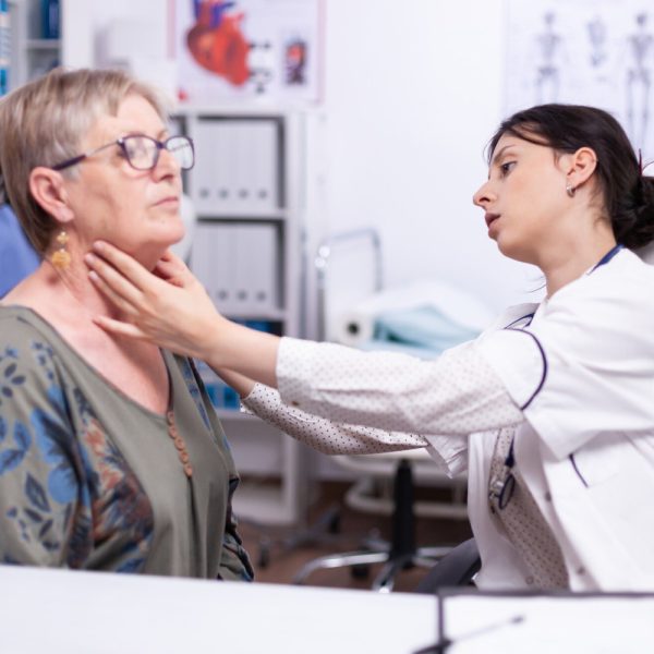 Endocrinologist examining patient with thyroid issue using AI Scribe for Endocrinologists support.