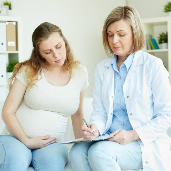 Gynecologist consulting pregnant patient and documenting care with AI Scribe for Gynecologists